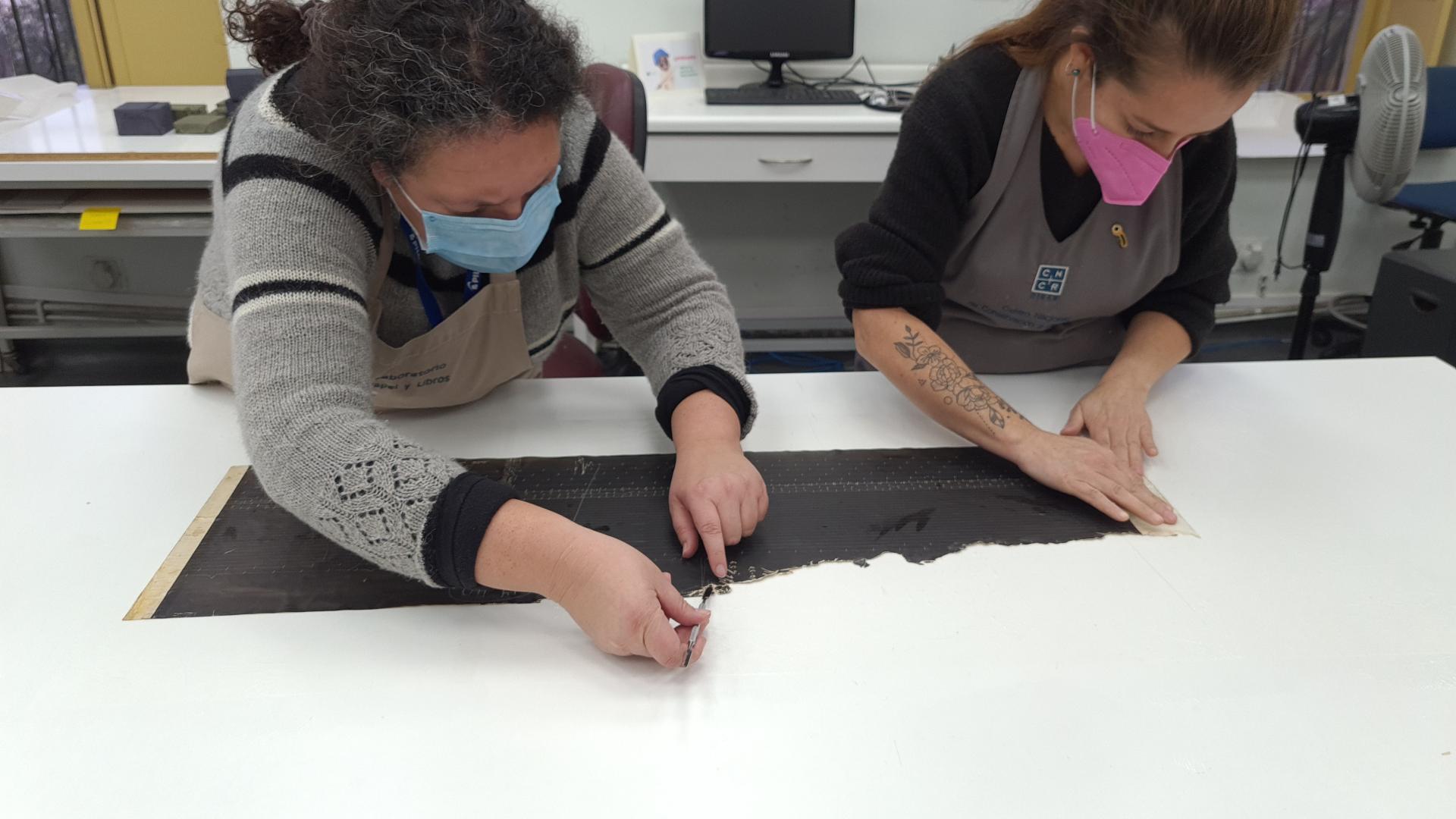 Figura 39. Claudia Pradenas y Vianka Hortuvia durante el proceso de laminado (Fotografía: Pinilla Rodríguez, O. 2021. Archivo CNCR. UPGD901.29). 